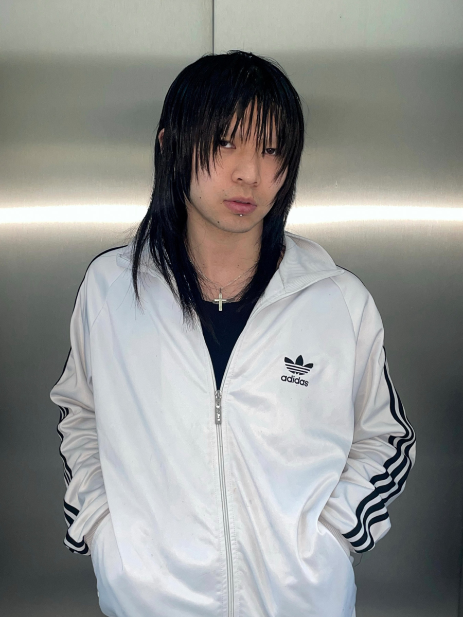 Taiga Sato in a white Adidas jacket standing against a metallic background, embodying modern urban style and artistic expression.