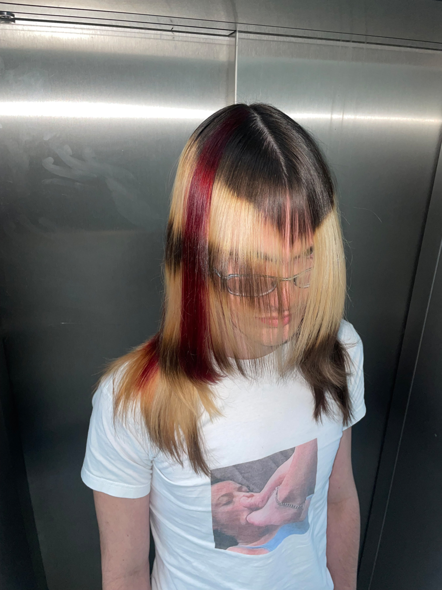 Model with straight, multi-tonal hair featuring contrasting black, blonde, and bold red streaks, styled in a sleek geometric look by Taiga Sato.