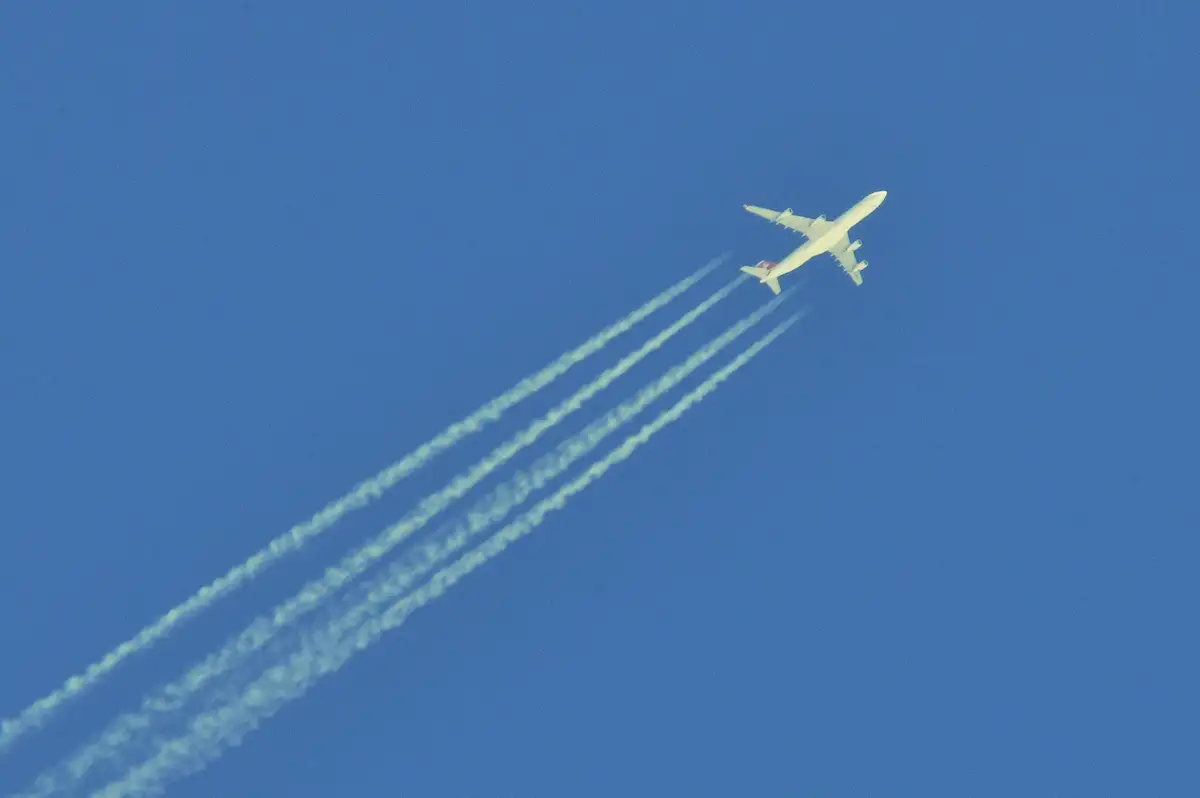 Kondensstreifen hinter einem Flugzeug vor klarem blauen Himmel.