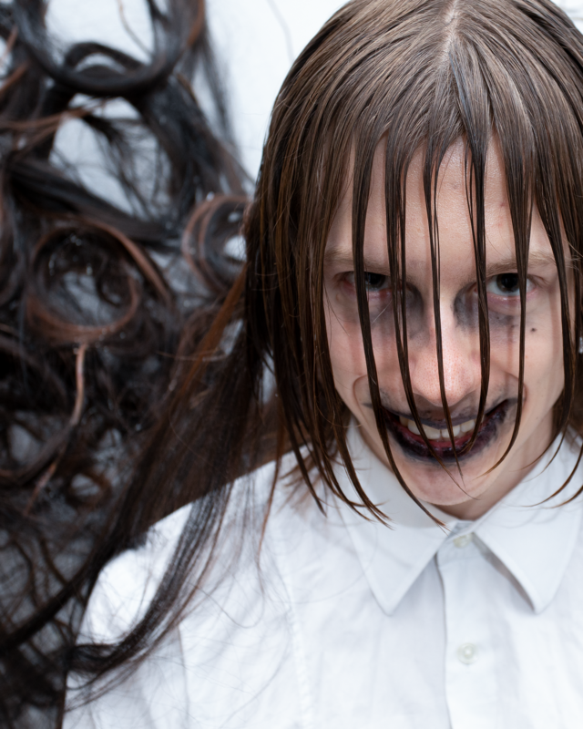 Close-up portrait of a model styled as ‘The Ghost,’ featuring long wet hair and dramatic makeup, including dark lipstick and eyeliner. Styled and directed by Taiga Sato for Infringe Magazine.