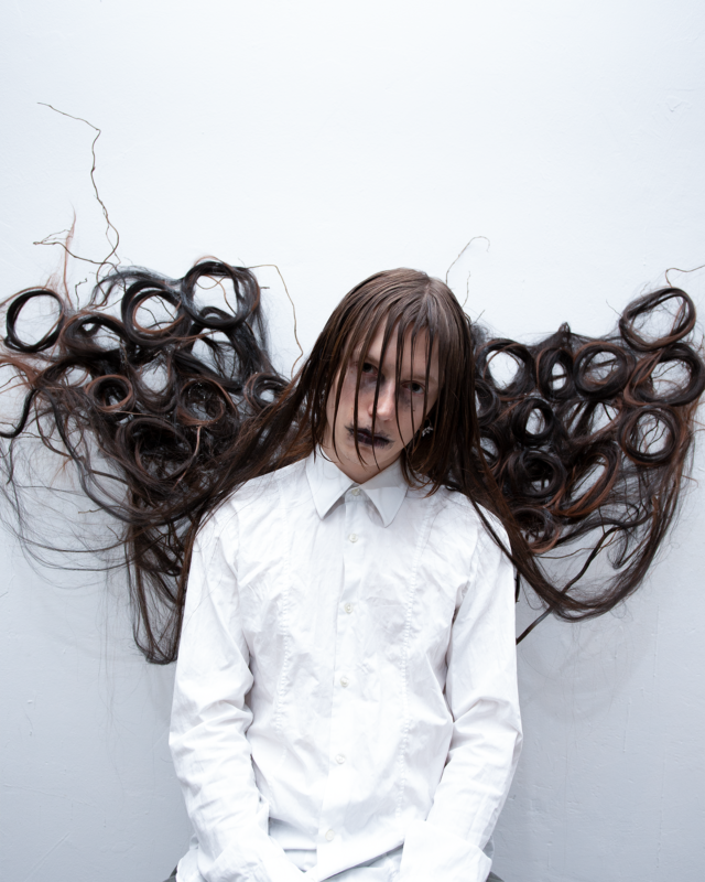 Artistic portrait titled ‘The Ghost,’ featuring a model with wet, long hair styled into looped patterns resembling wings. Styled and directed by Taiga Sato for Infringe Magazine